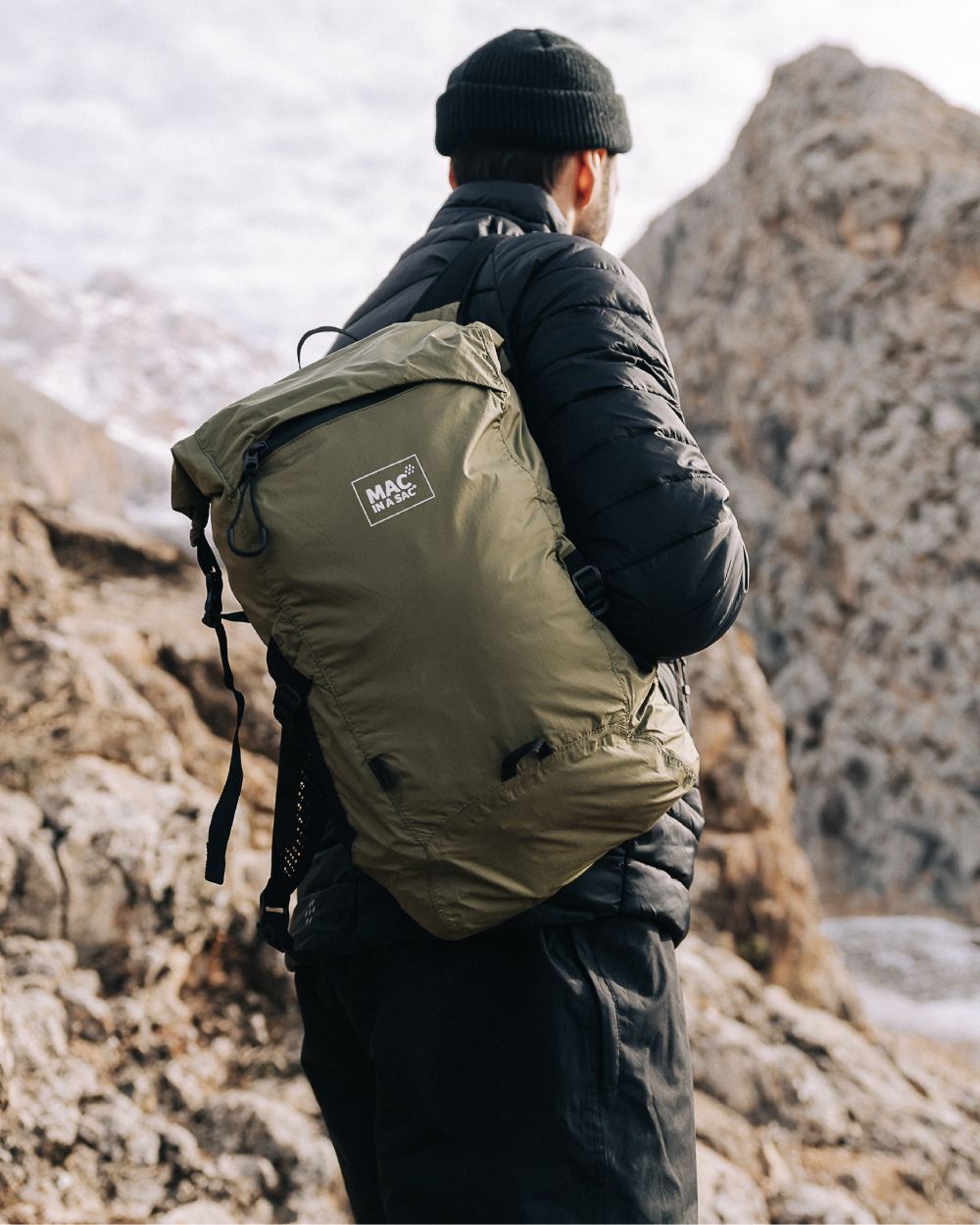 Khaki coloured Mac In A Sac Travelite Packable Waterproof Backpack on mountain background 