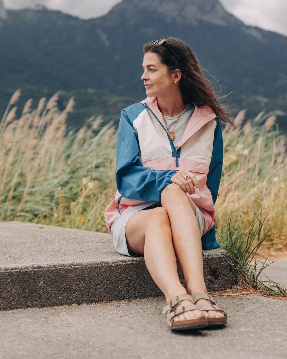 Teal Pink coloured Mac In A Sac Womens Nomad Waterproof Half Zip Jacket on mountain background 