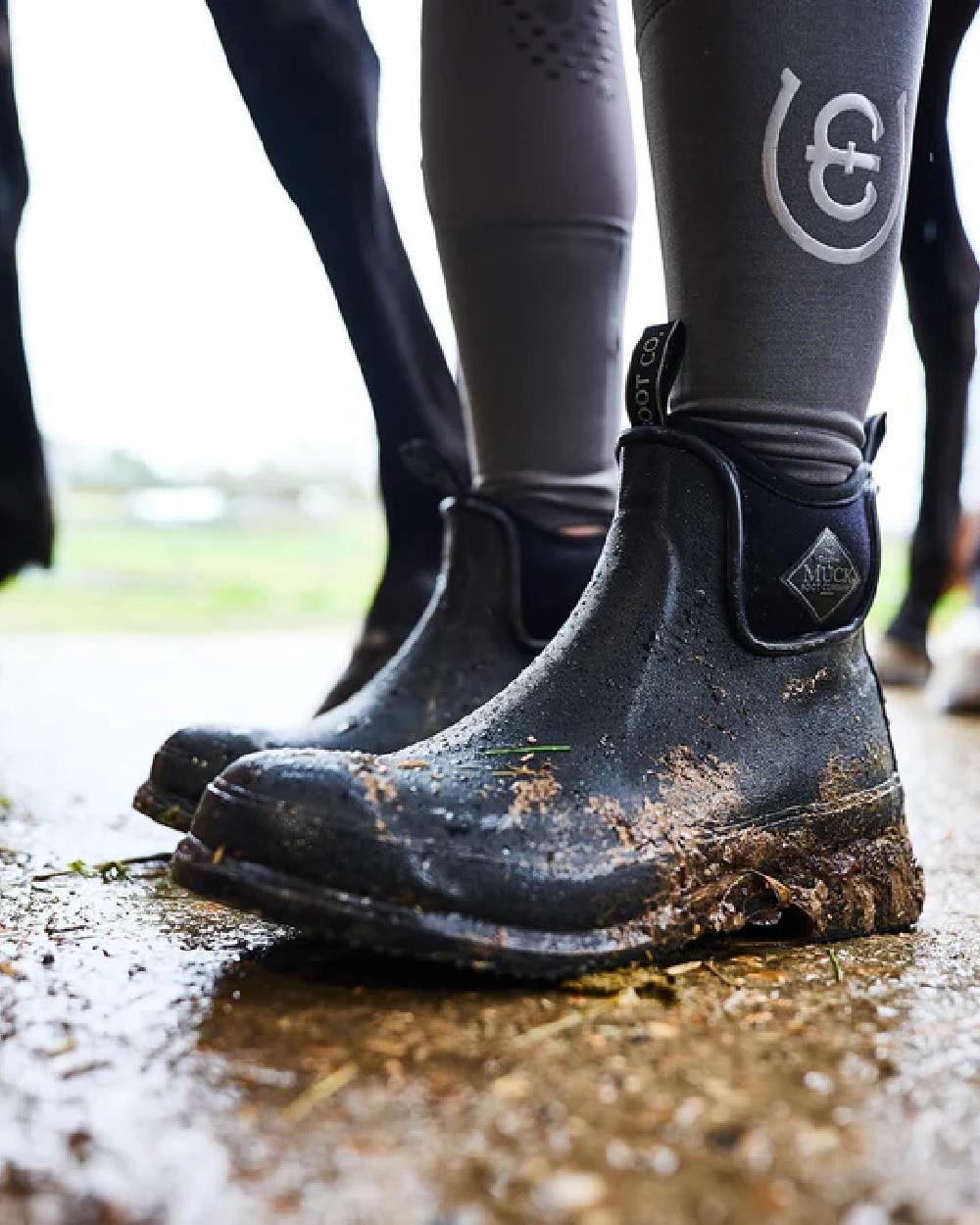 Black Coloured Muck Boots Wear Ankle Boots on ground background 