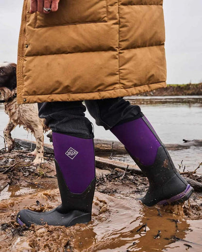 Black Acai coloured Muck Boots Womens Artic Sport II Tall Wellingtons on muddy background 