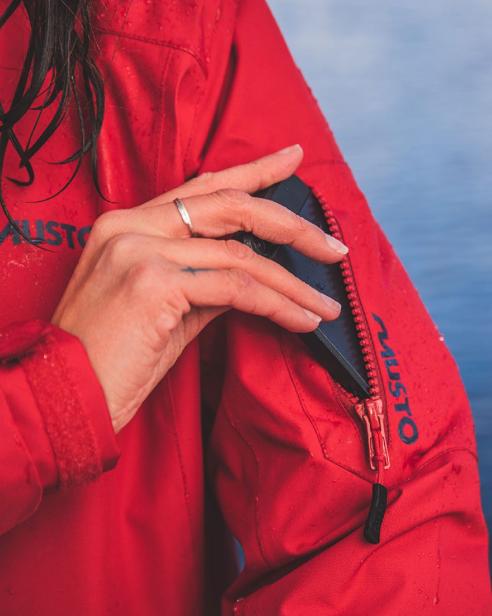 Red coloured Musto Ladies Sardinia Long Rain Jacket on sky background 