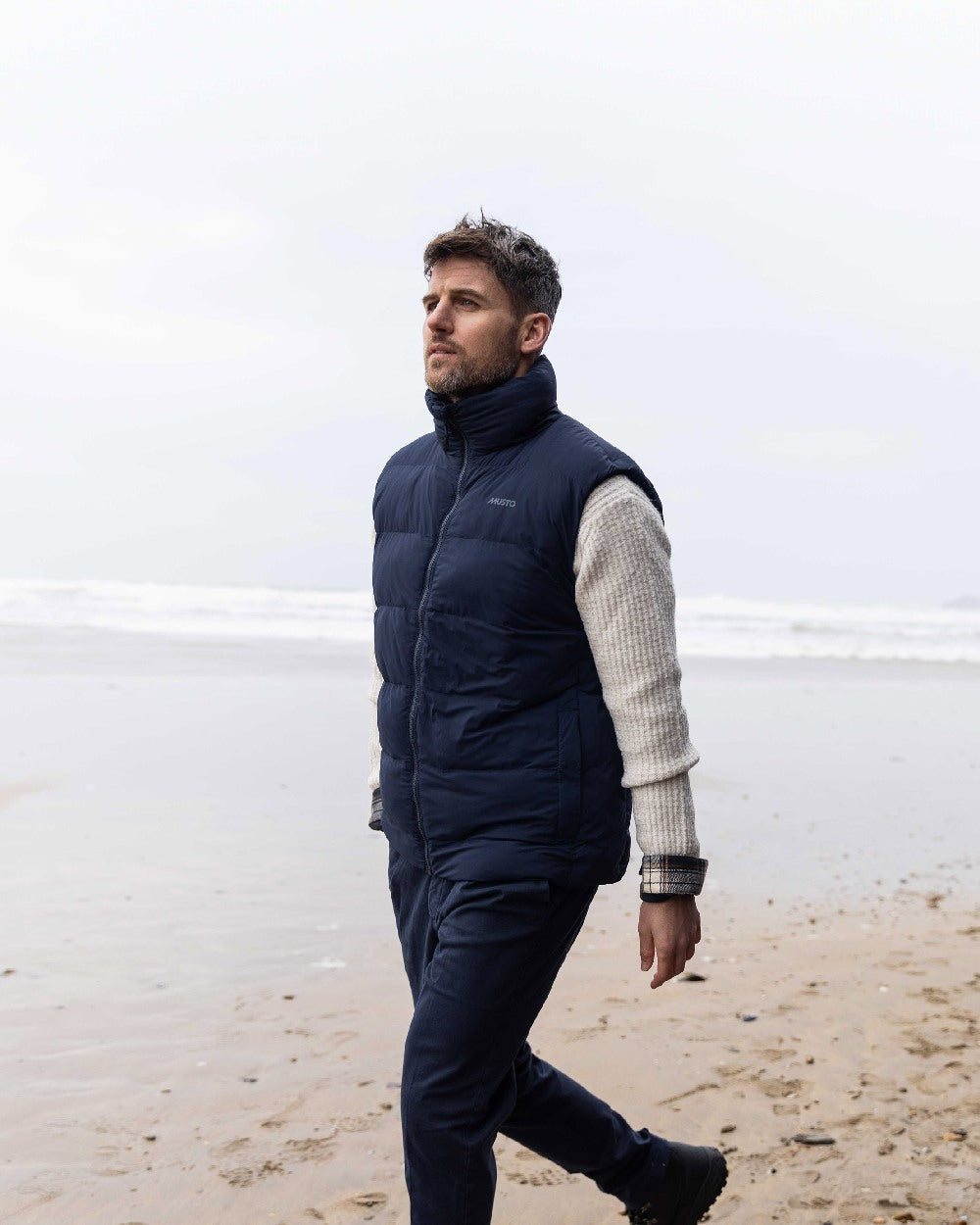 Navy Coloured Musto Mens Active Puffer Vest on beach background 