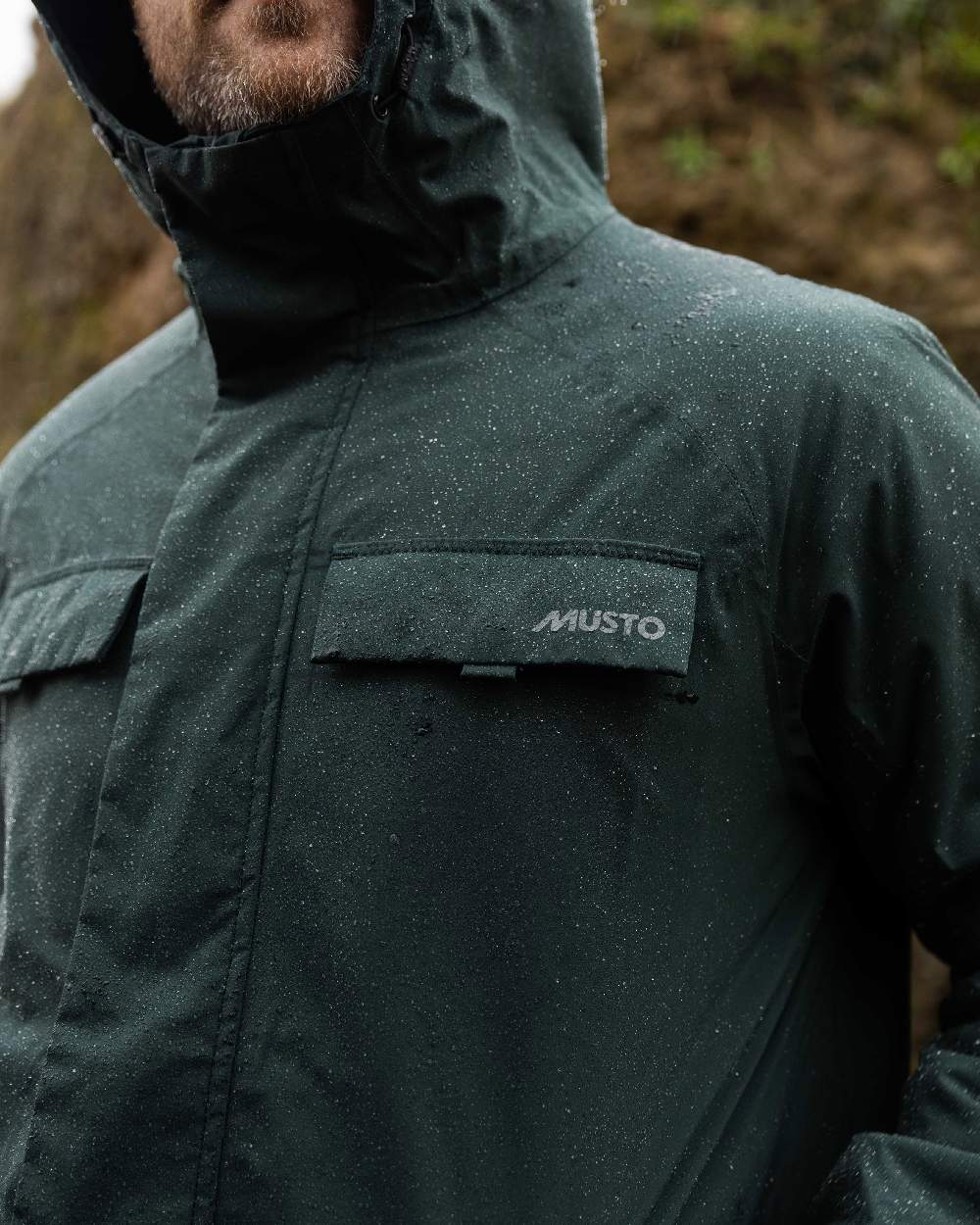 Darkest Spruce Coloured Musto Mens Insulated Rain Jacket on blurry background 