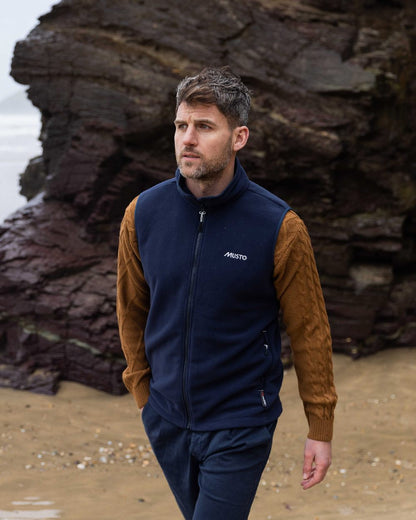 Navy Coloured Musto Mens Nautic Polartec Fleece Vest on beach background 