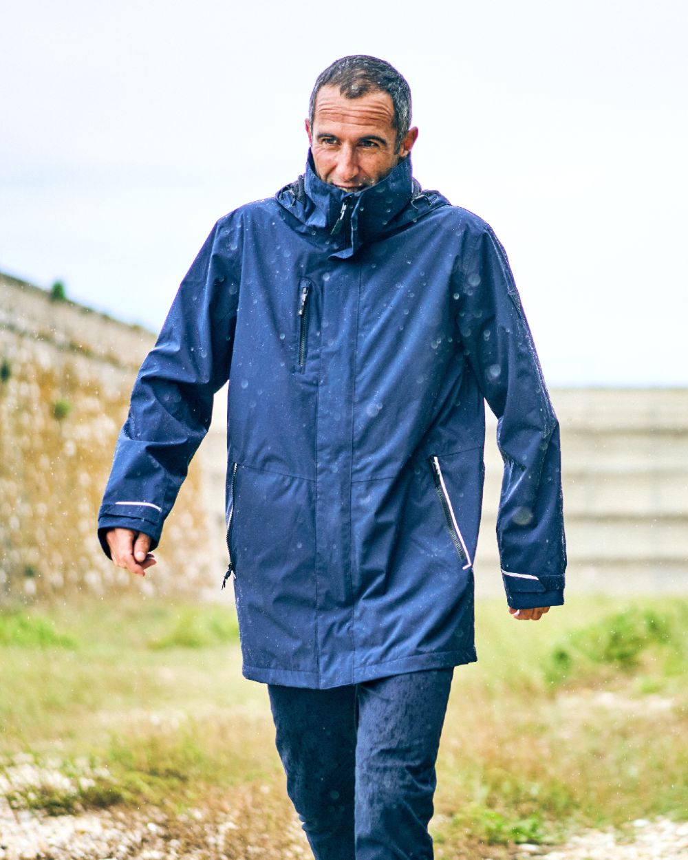 Navy coloured Musto Sardinia Long Rain Jacket on blurry background 