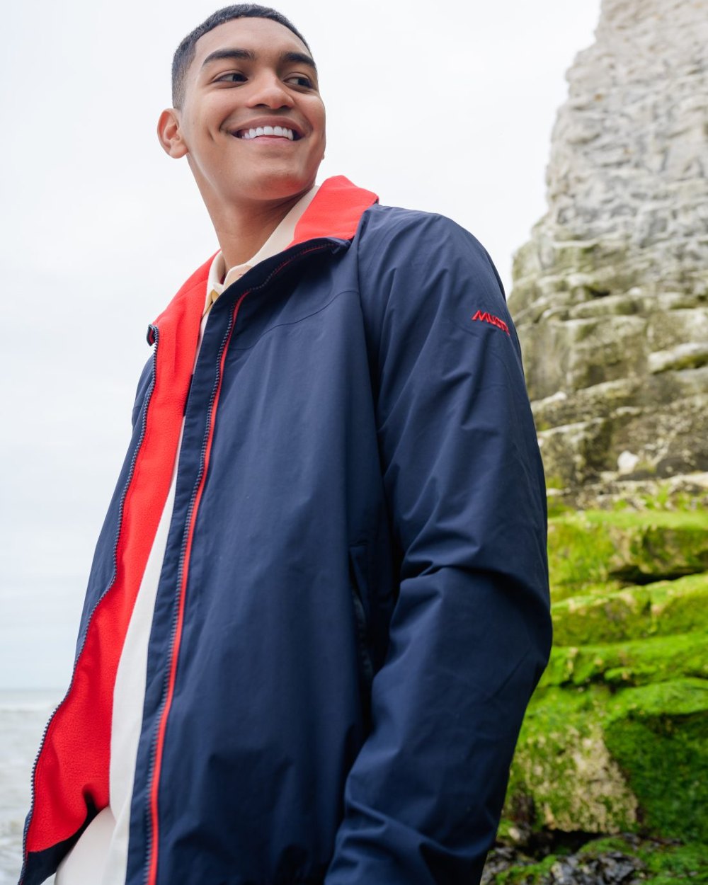 Navy Red coloured Musto Snug Blouson Jacket 2.0 on blurry mountain background 