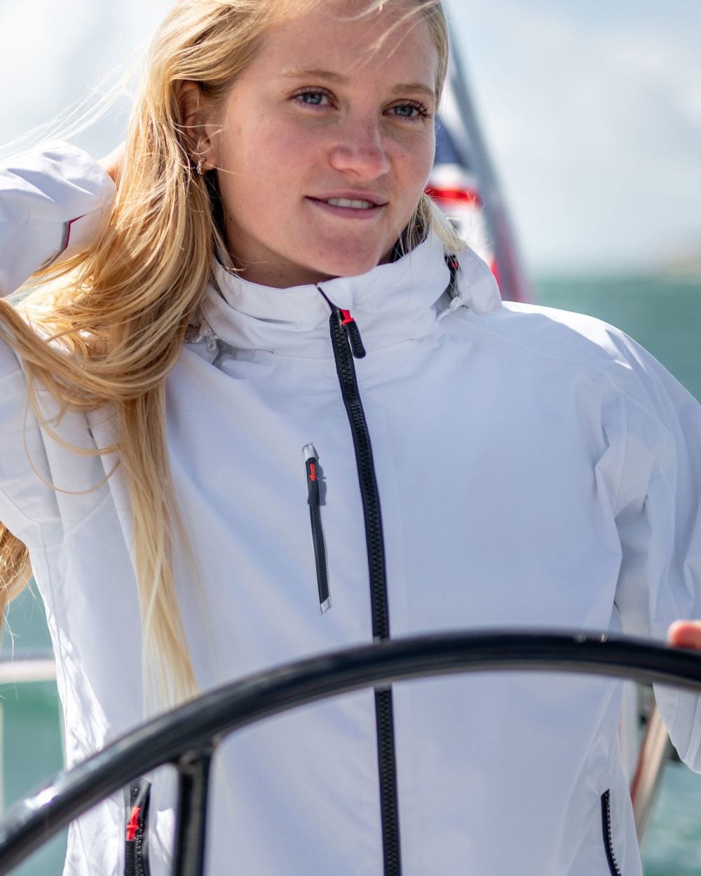 Platinum coloured Musto Womens Sardinia Jacket 2.0 on Blurry Ocean background 