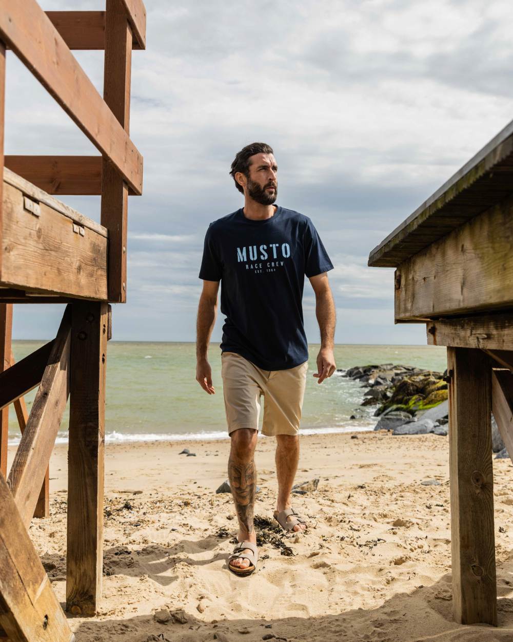 Navy Coloured Musto Mens Classic Short Sleeve T-Shirt On A Beach Background 