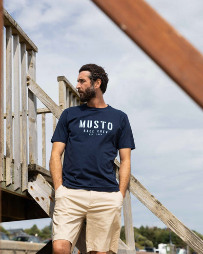 Navy Coloured Musto Mens Classic Short Sleeve T-Shirt On A Coastal Background 