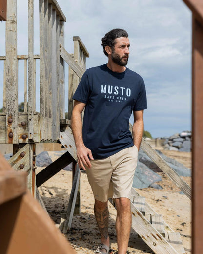 Navy Coloured Musto Mens Classic Short Sleeve T-Shirt On A Beach Background 