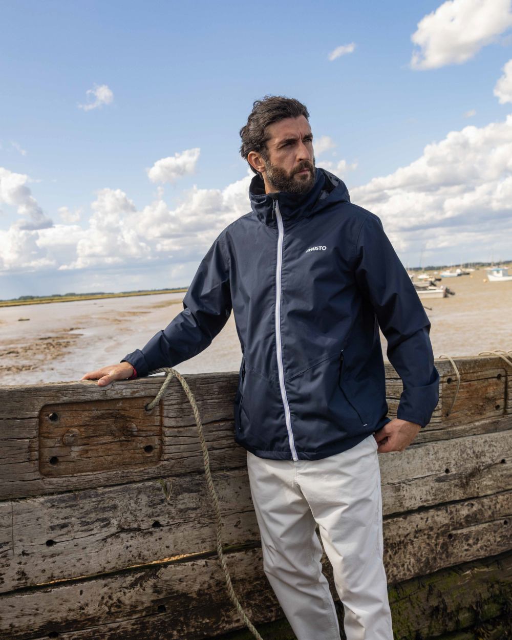 Navy Coloured Musto Mens Nautic Rain Jacket On A Coastal Background 