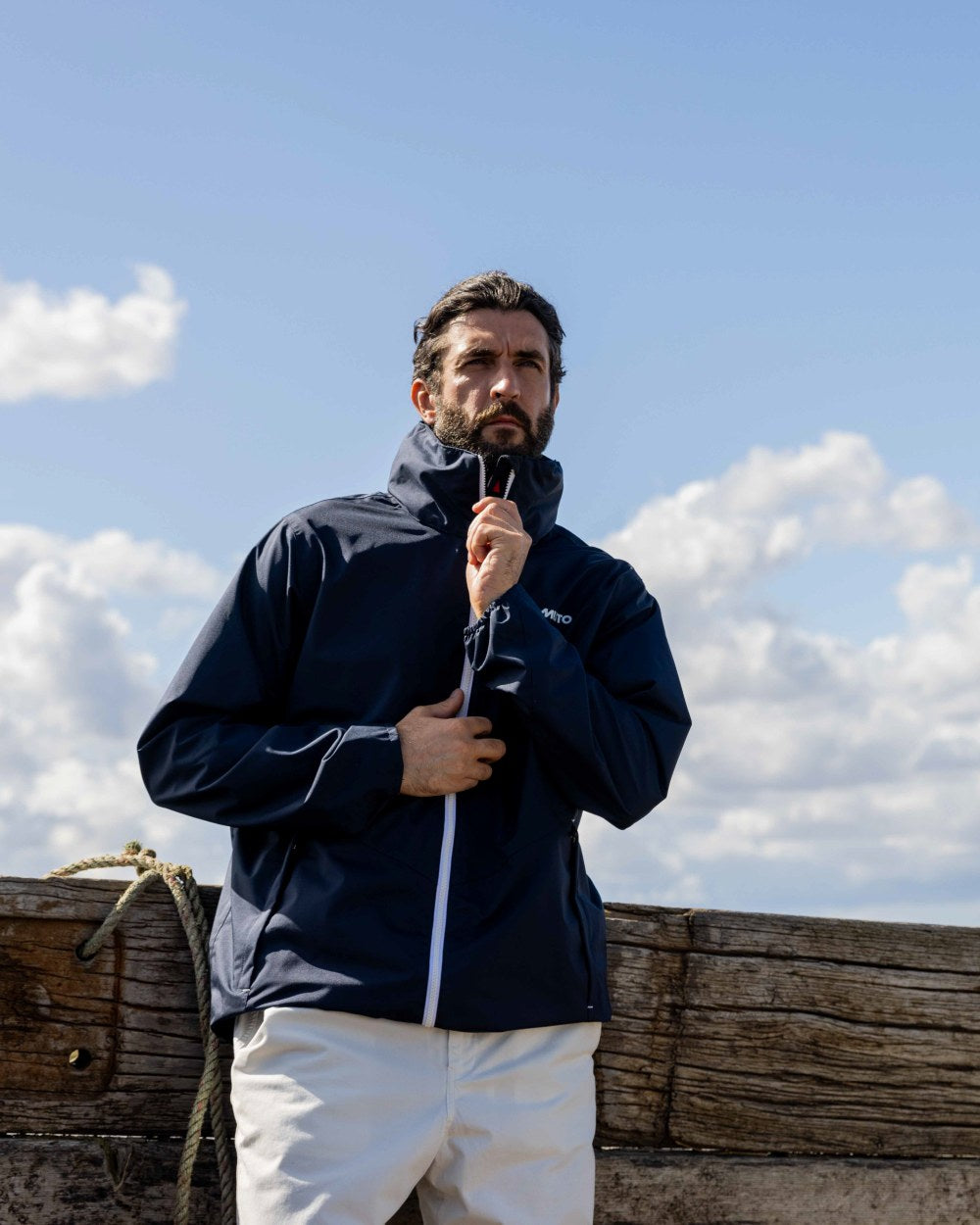 Navy Coloured Musto Mens Nautic Rain Jacket On A Coastal Background 