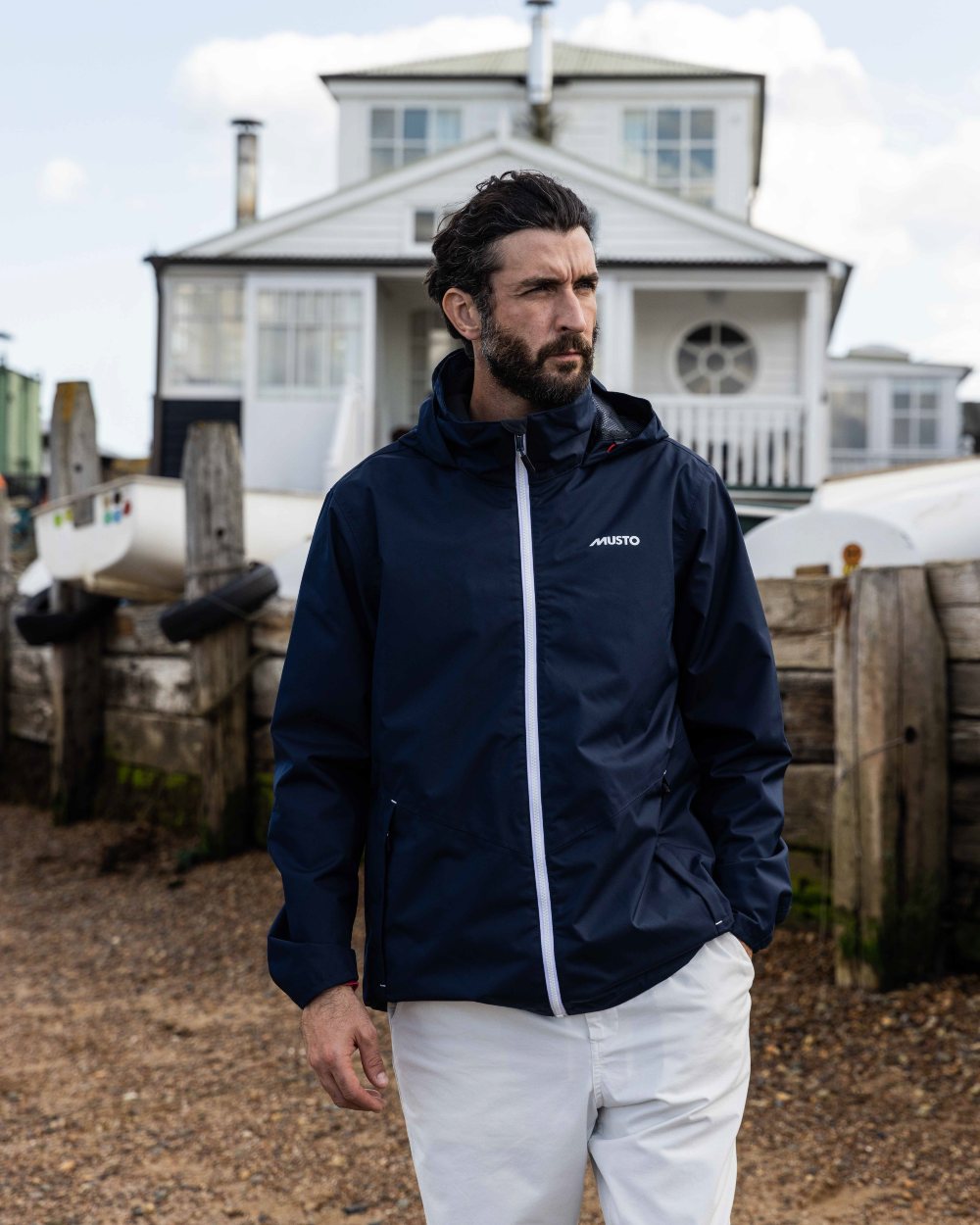 Navy Coloured Musto Mens Nautic Rain Jacket On A Coastal Background 