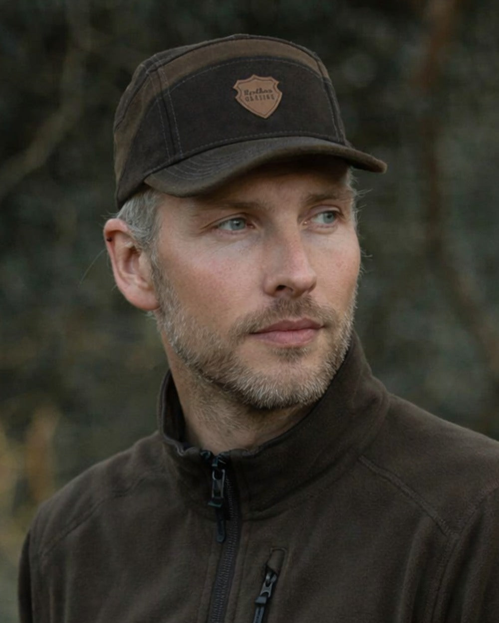 Dark Green coloured Northern Hunting Roald Cap on forest background 