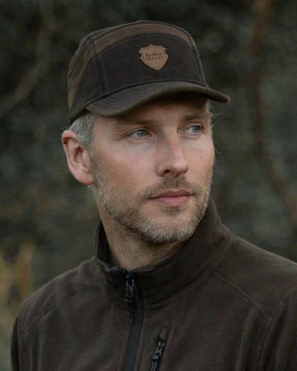 Dark Green coloured Northern Hunting Roald Cap on forest background 