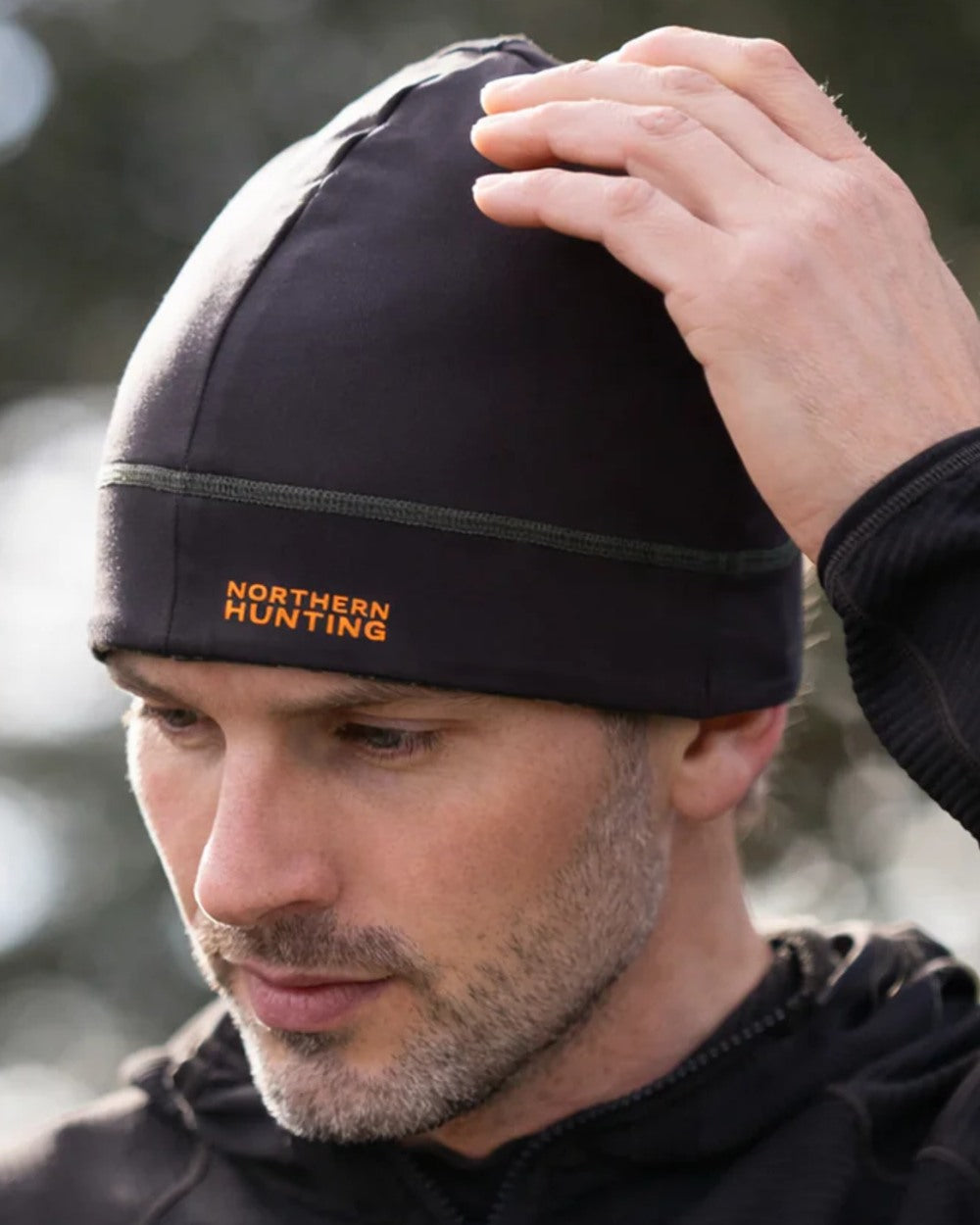 Dark Green Opt2 coloured Northern Hunting Rune Reversible Stretch Beanie on forest background 