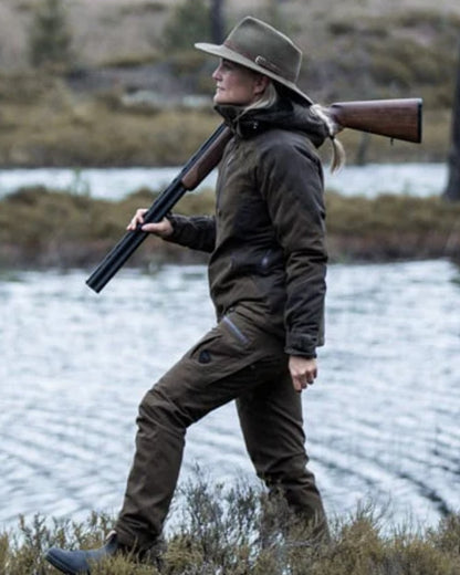 Green coloured Northern Hunting Womens Elk Ragna Waterproof Jacket on forest background 
