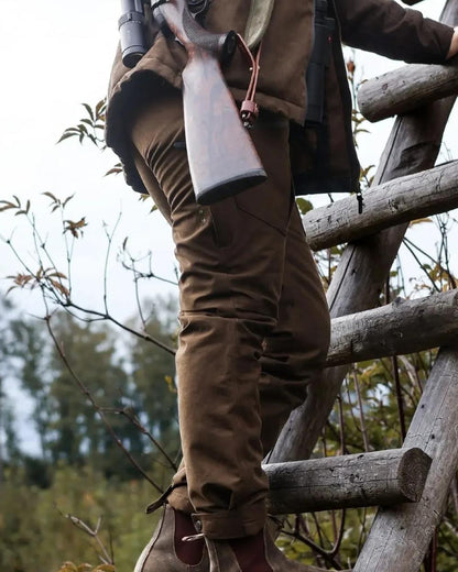 Green coloured Northern Hunting Womens Elk Svana Hunting Trousers on forest background 