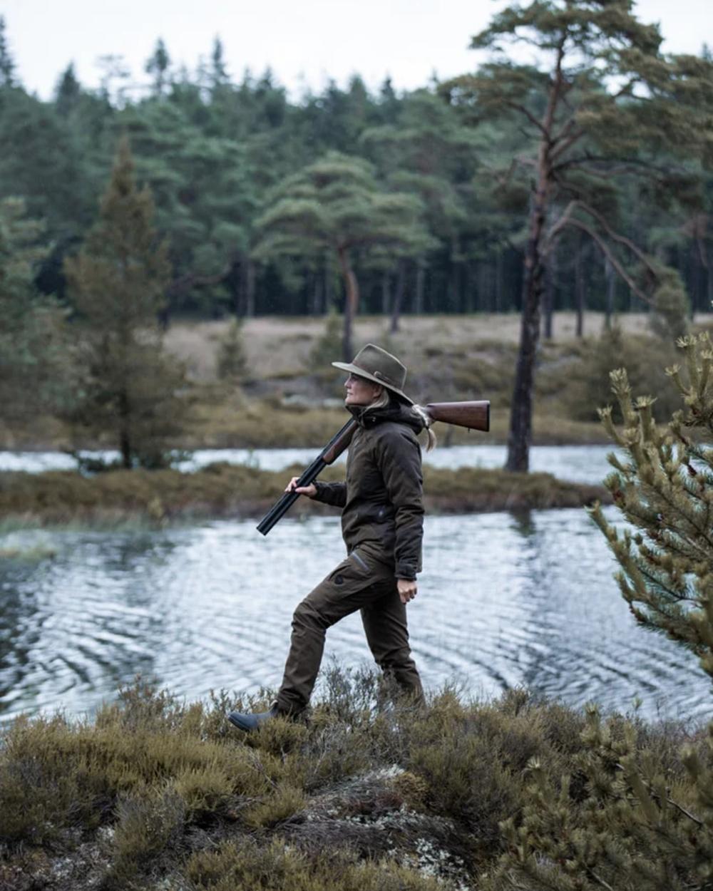 Green coloured Northern Hunting Womens Elk Ragna Waterproof Jacket on forest background 