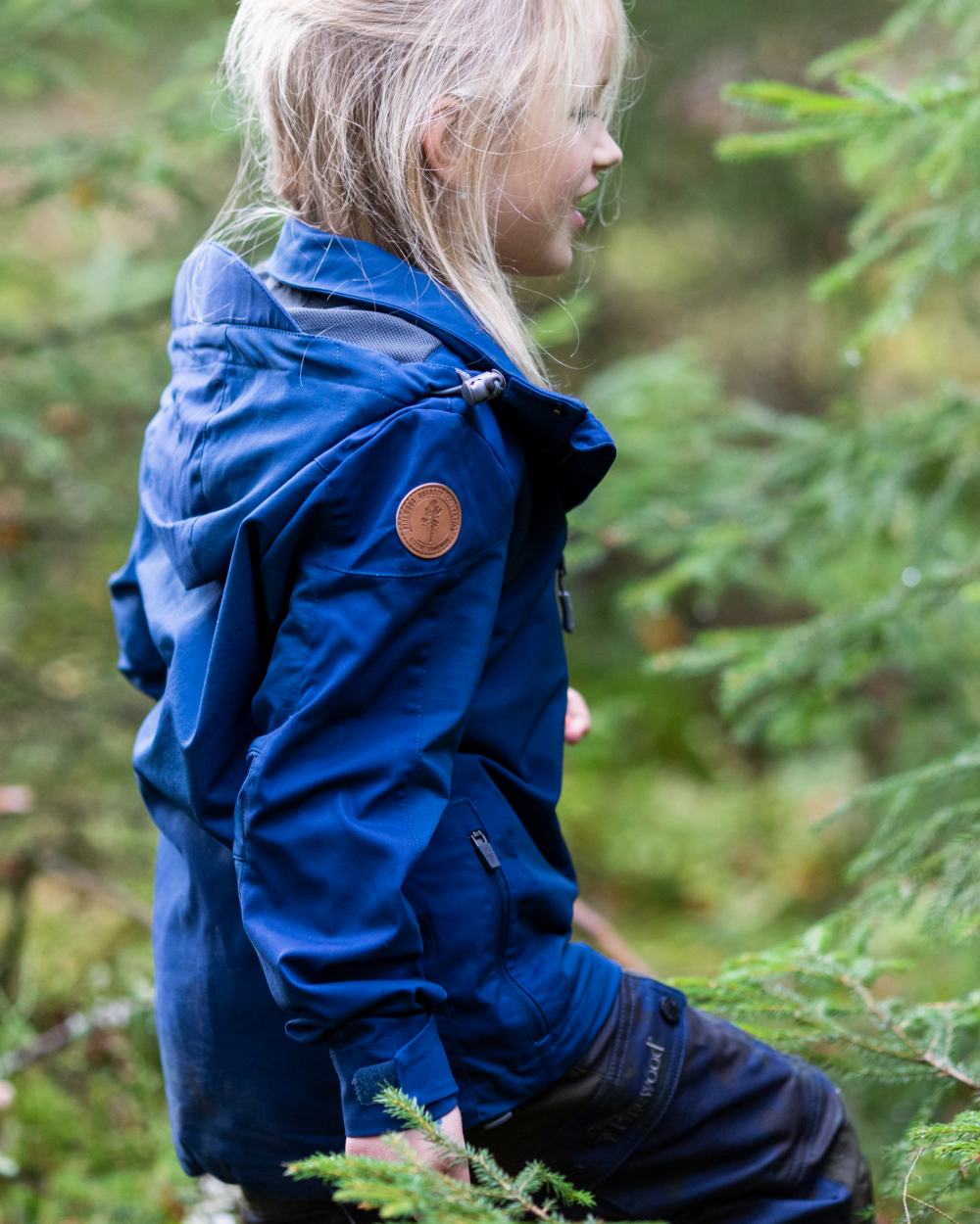 Dark Dive coloured Pinewood Childrens Finnveden Hybrid Jacket on forest background 