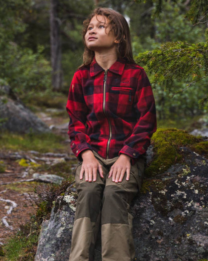 Olive Moss Green coloured Pinewood Childrens Lappland Trousers on forest background 