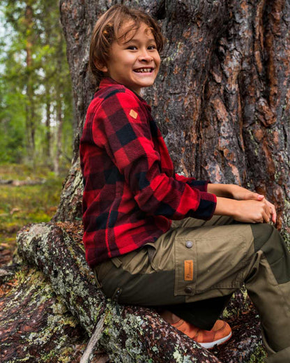 Olive Moss Green coloured Pinewood Childrens Lappland Trousers on forest background 