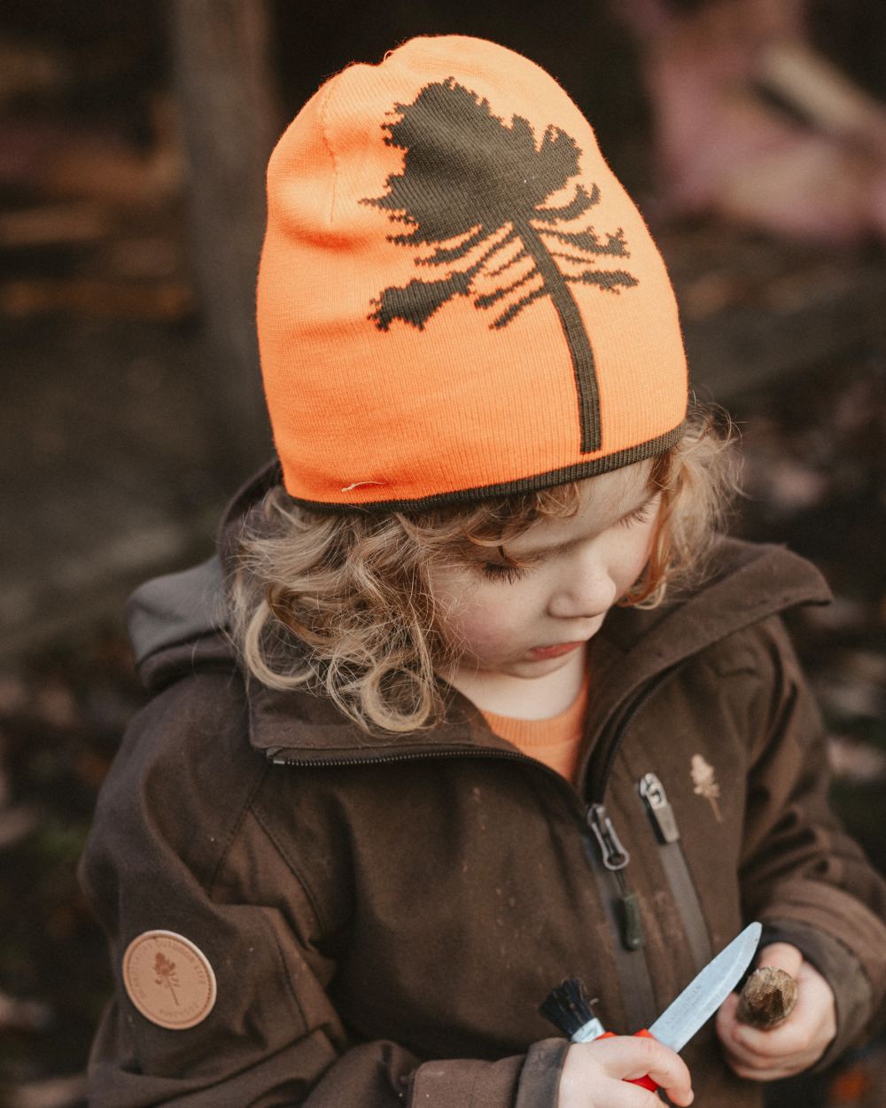 Orange Green coloured Pinewood Childrens Tree Hat on forest background 