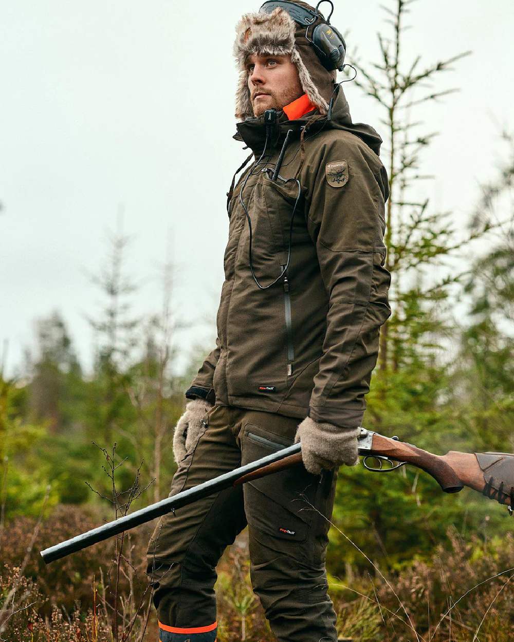 Moss Green coloured Pinewood Mens Hunter Pro Extreme 2.0 Trousers on forest background 