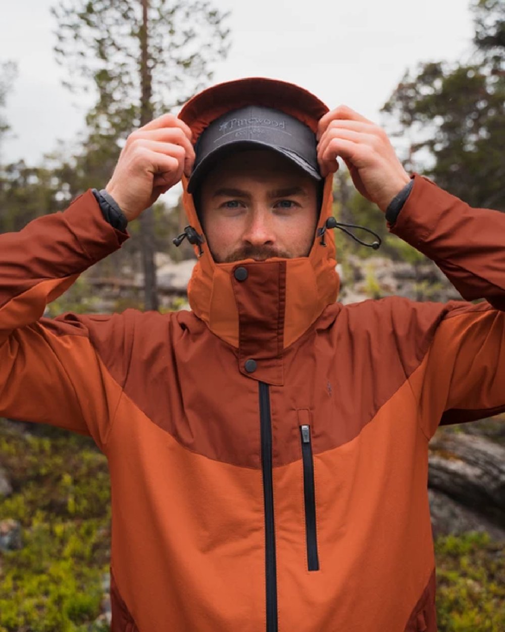 Terracotta coloured Pinewood Mens Finnveden Hybrid Jacket on forest background 
