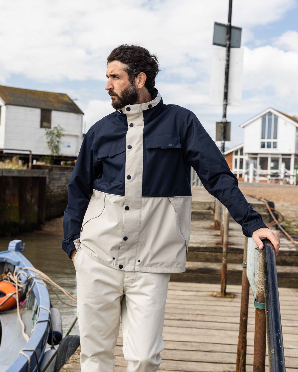 Pumice/Navy Coloured Musto Mens Classic Shore Waterproof Jacket On A Coastal Background 