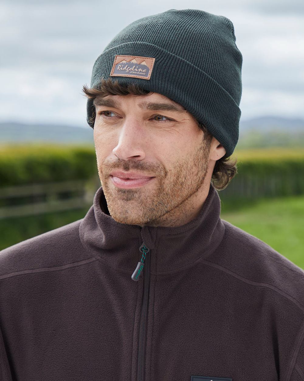 Deep Forest coloured Ridgeline Heritage Fine Knit Beanie on grassy background 