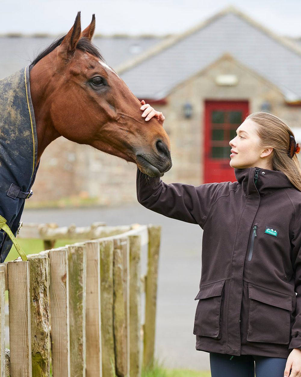 Deep Bark coloured Ridgeline Ladies Rhea Jacket on farm background 