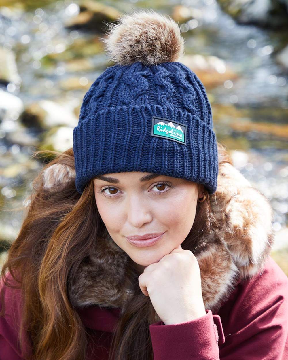 Navy coloured Ridgeline Nordic Fleck Bobble Hat on water background 