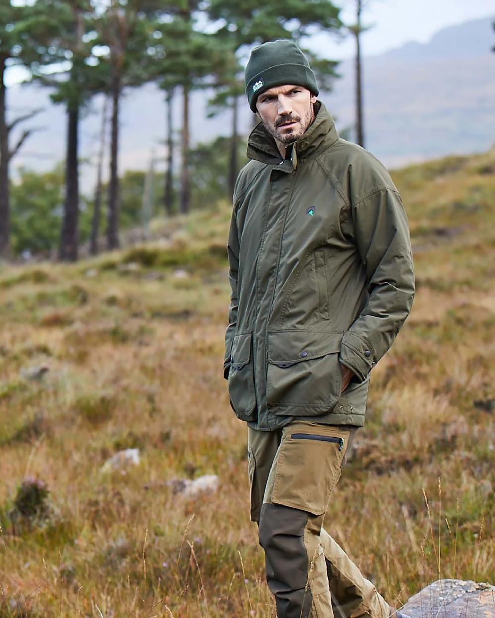 Olive Ridgeline Sovereign Field Coat on blurry mountain background 