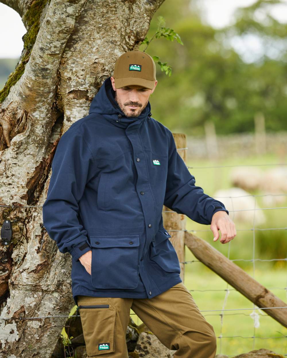 Navy coloured Ridgeline Torrent III Waterproof Jacket on blurry tree background 