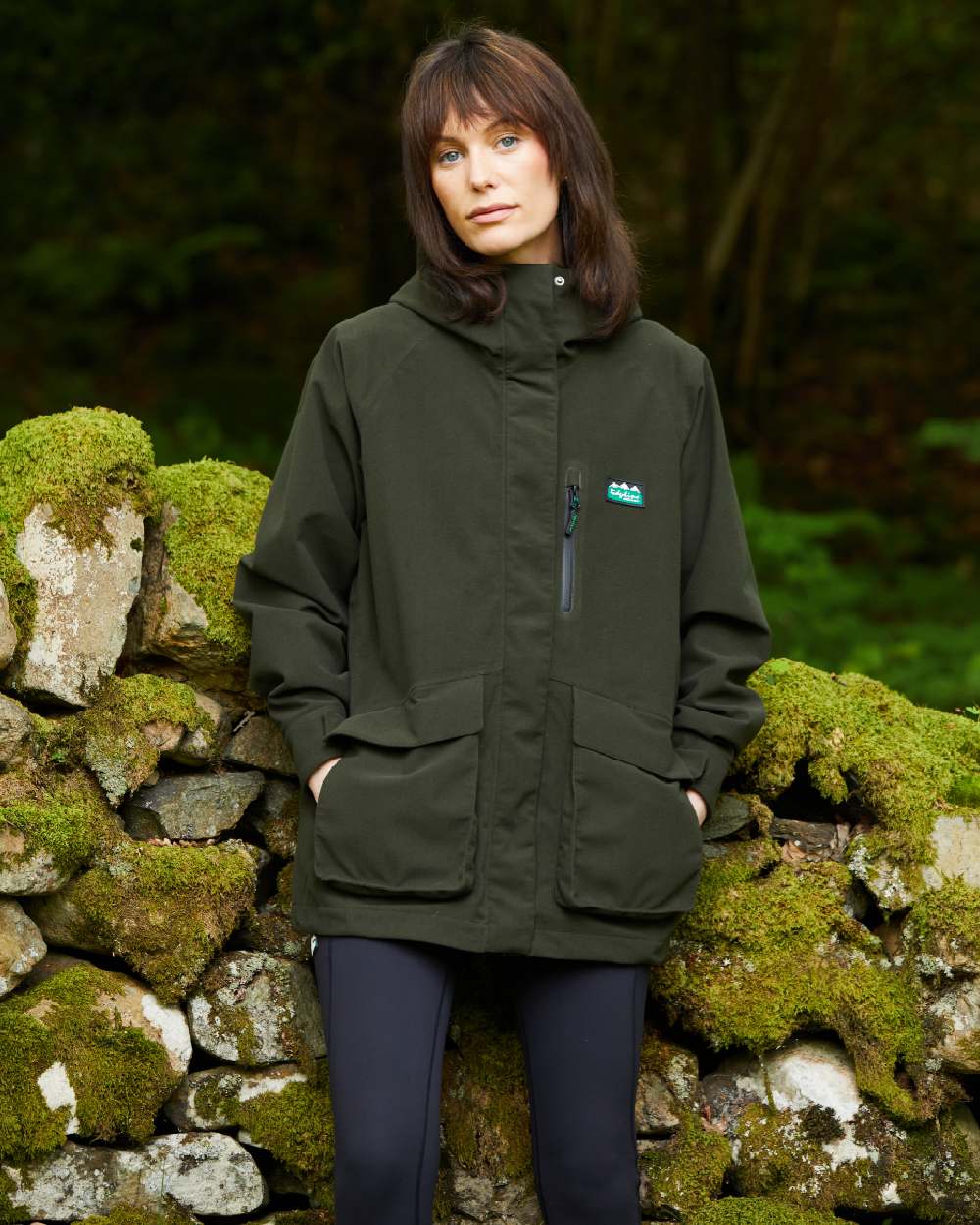 Deep Forest coloured Ridgeline Womens Rhea Jacket on stone wall background 