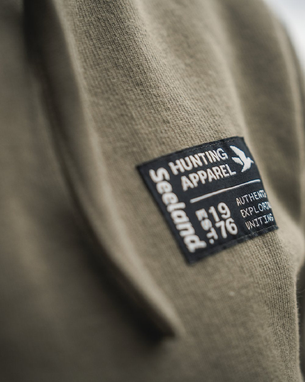 Grape Leaf Coloured Seeland Delta Hoodie on Blurry Background
