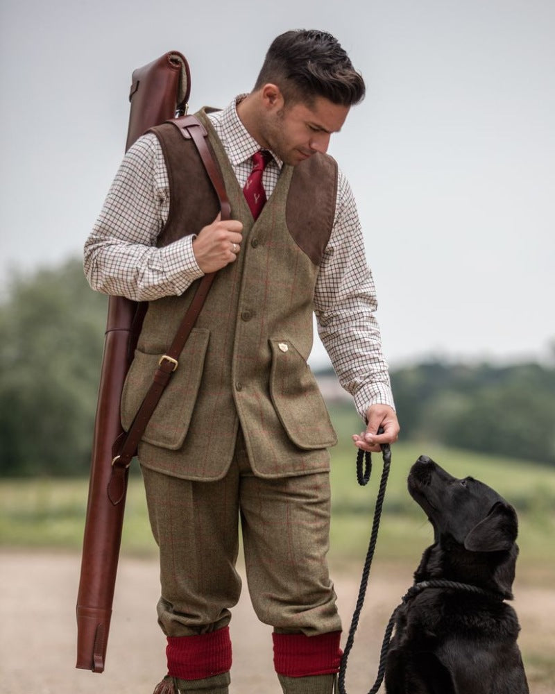 Man wearing an Alan Paine tweed shooting outfit while walking a black Labrador outdoors