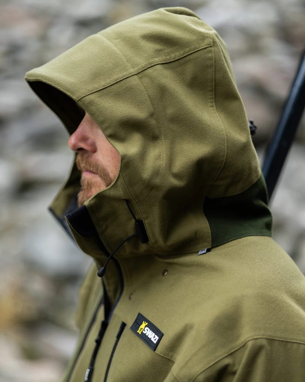 Tussock Green coloured Swazi The Ibex Jacket on blurry background 