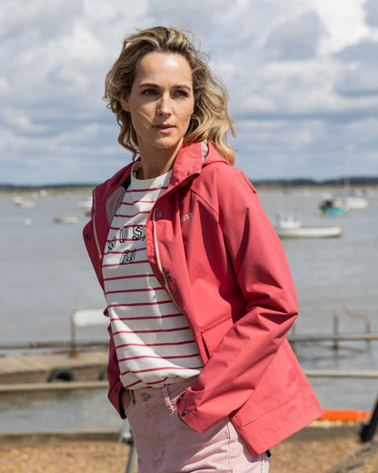Sweet Raspberry Coloured Musto Womens Classic Shore Waterproof Jacket On A Beach Background 