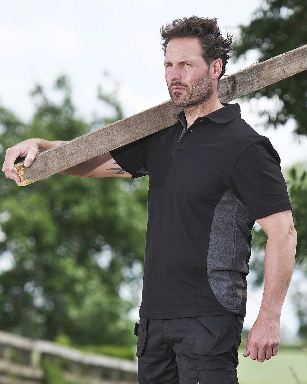 Man carrying plank wearing Tuffstuff Pro Work Polo Shirt in Black 
