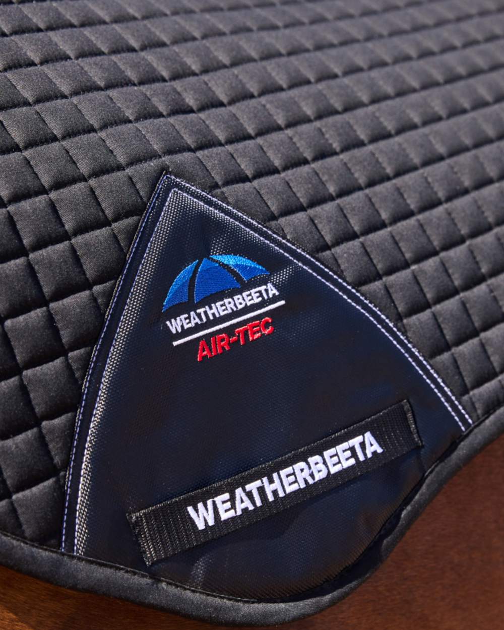Black Coloured WeatherBeeta Prime Air-Tec Jump Shaped Saddle Pad on horse  background 