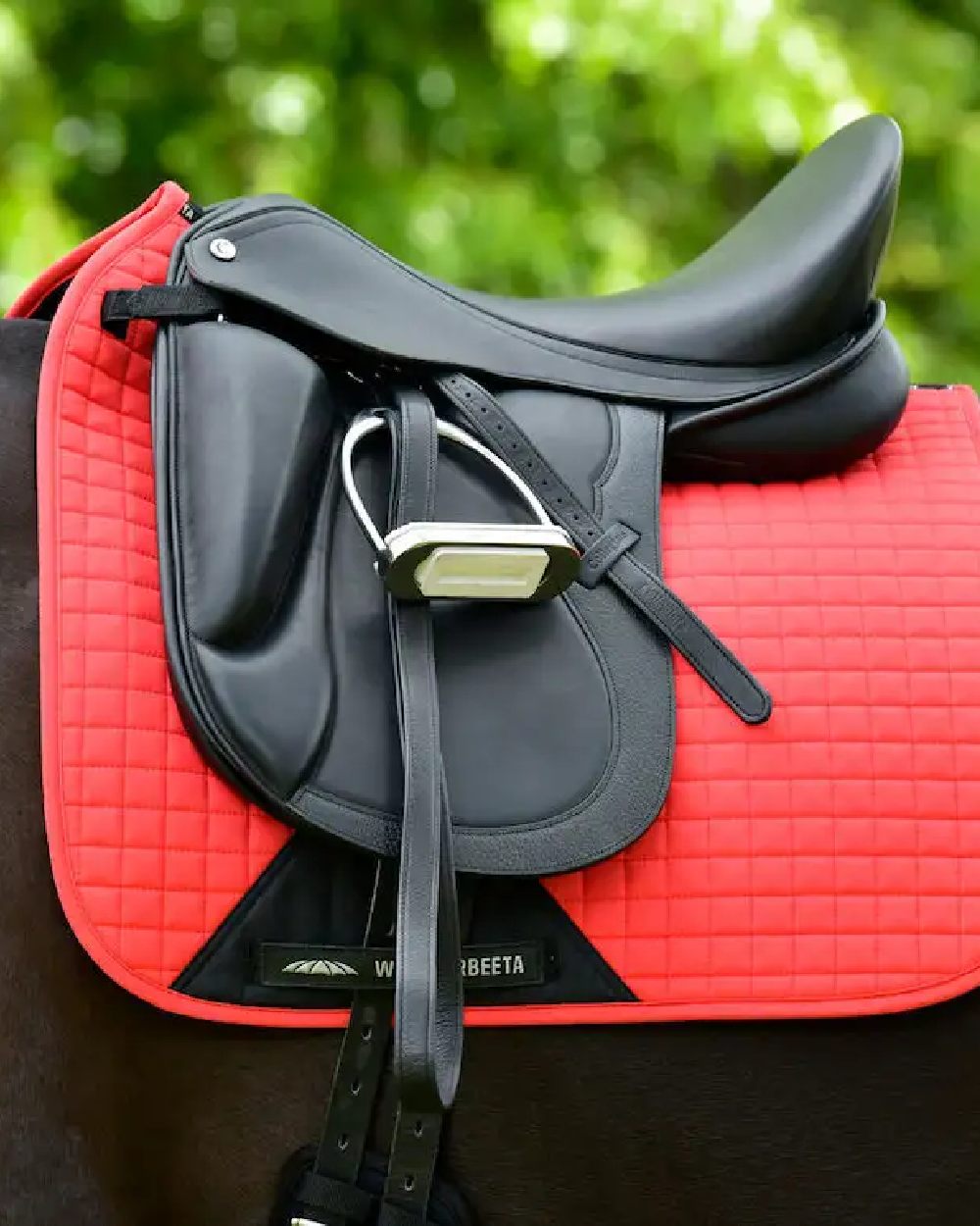 Bittersweet Red coloured WeatherBeeta Prime Dressage Saddle Pad on blurry background 