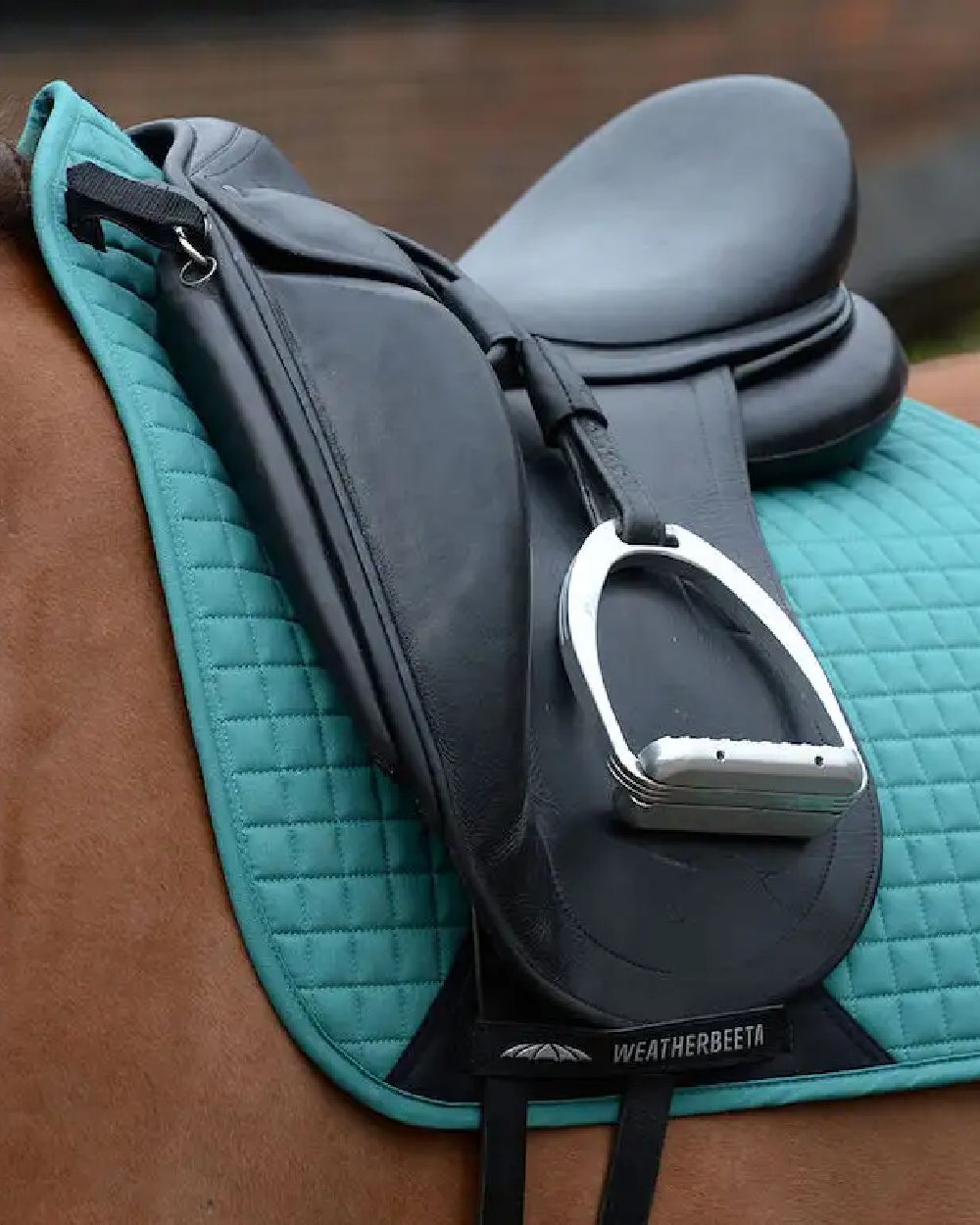 Green coloured WeatherBeeta Prime Dressage Saddle Pad on blurry background 