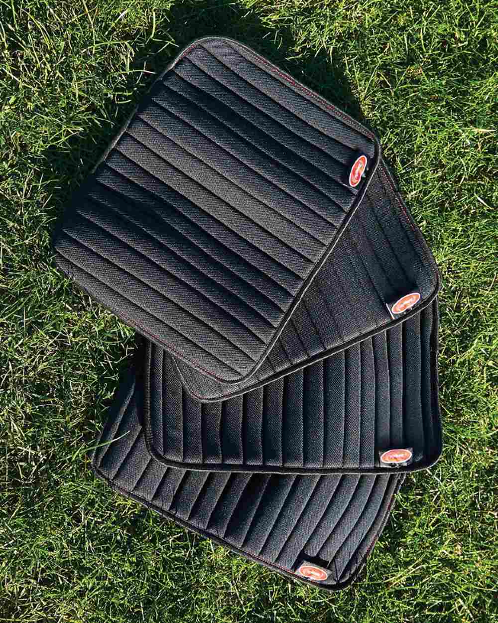 Black Red coloured WeatherBeeta Therapy-Tec Channel Quilt Leg Pads 4 Pack on grass background 