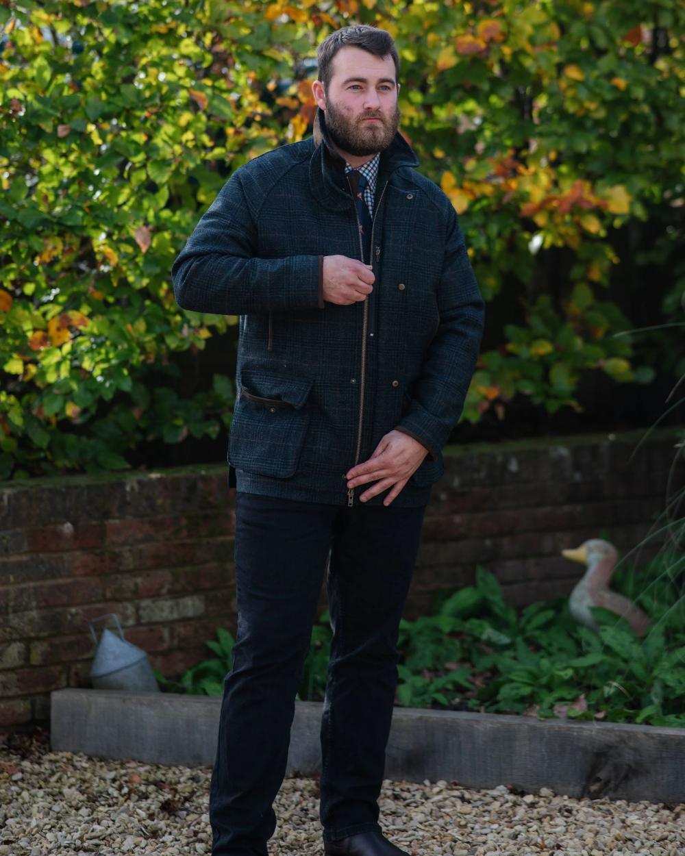 Green Check Coloured Alan Paine Surrey Waterproof Tweed Coat On A Leafy Background 