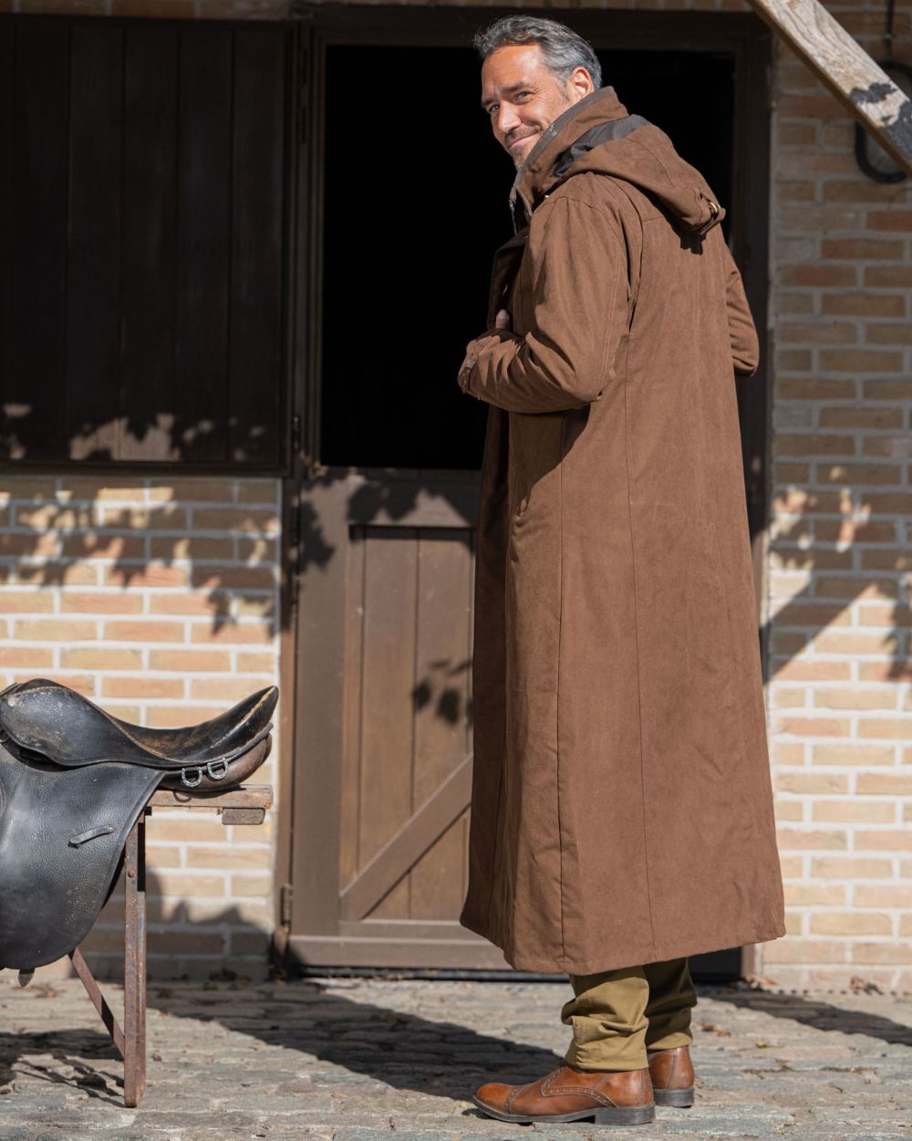 Earth Brown Coloured Baleno Livingstone Long Waterproof Coat On A Backyard Background 