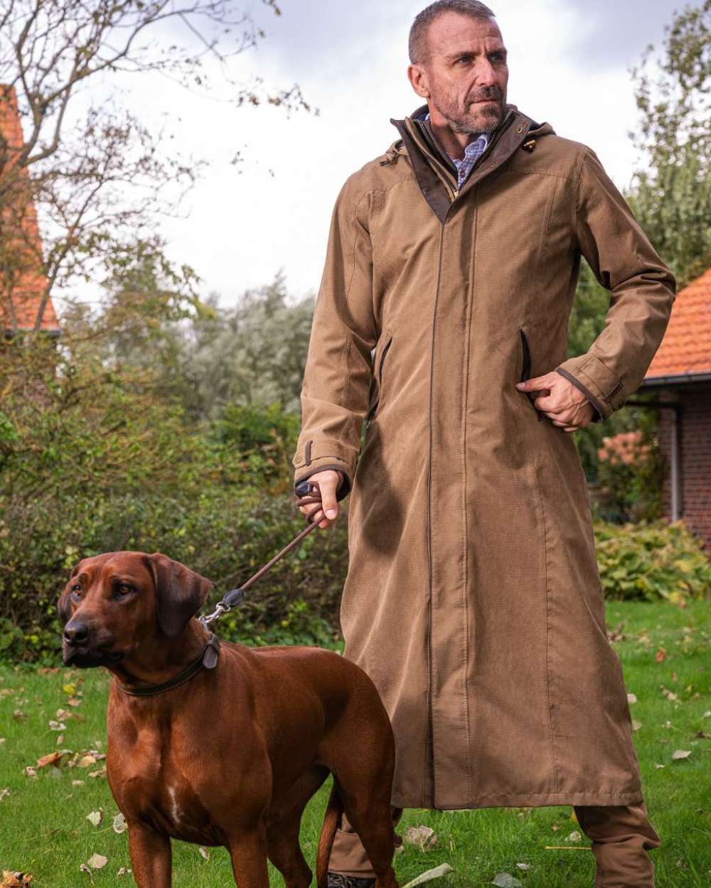 Camel Coloured Baleno Livingstone Long Waterproof Coat On A Backyard Background 