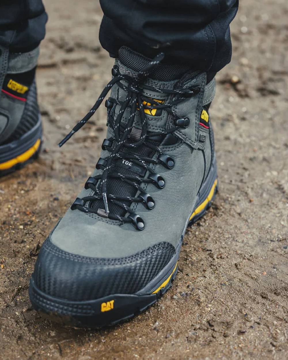 Dark Shadow Coloured Caterpillar Munising Safety Boot On A  Muddy Background