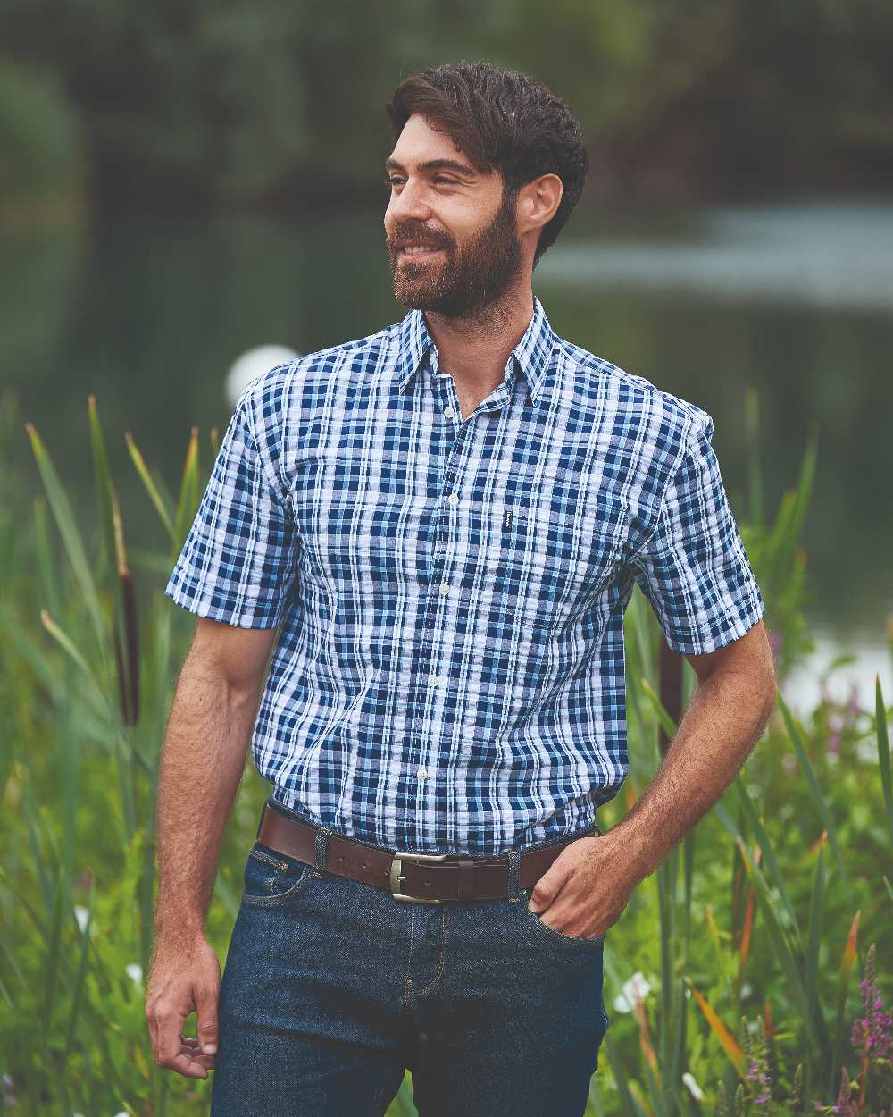 Blue coloured Champion Croyde Cotton Short Sleeved Shirt on blurry green background 